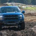 A blue 2017 Ford Raptor is shown from the front off-roading.