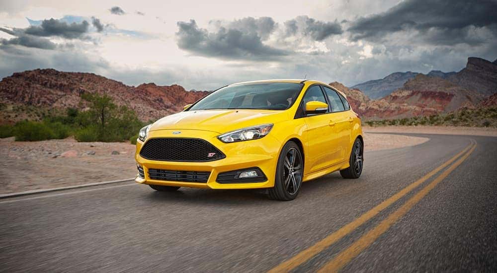 A yellow 2017 Ford Focus ST driving on an open road.