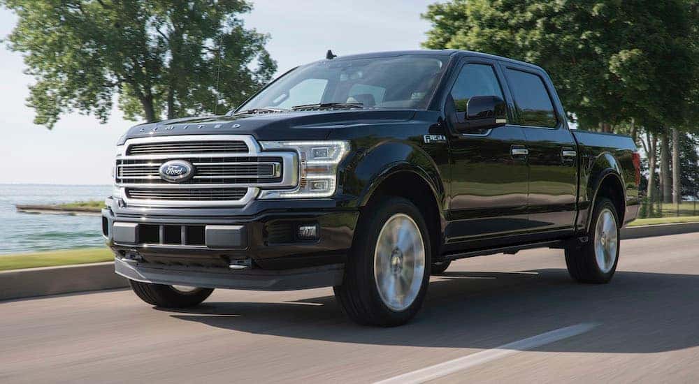 A black 2015 Ford F-150 Limited is driving on an open road.