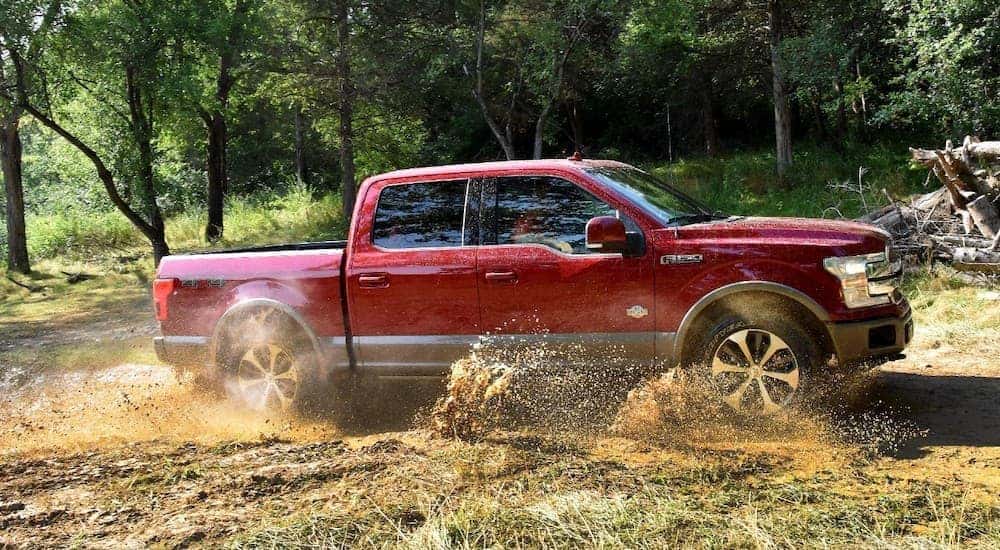 A red 2018 Ford F-150 is driving to a used Ford dealership.