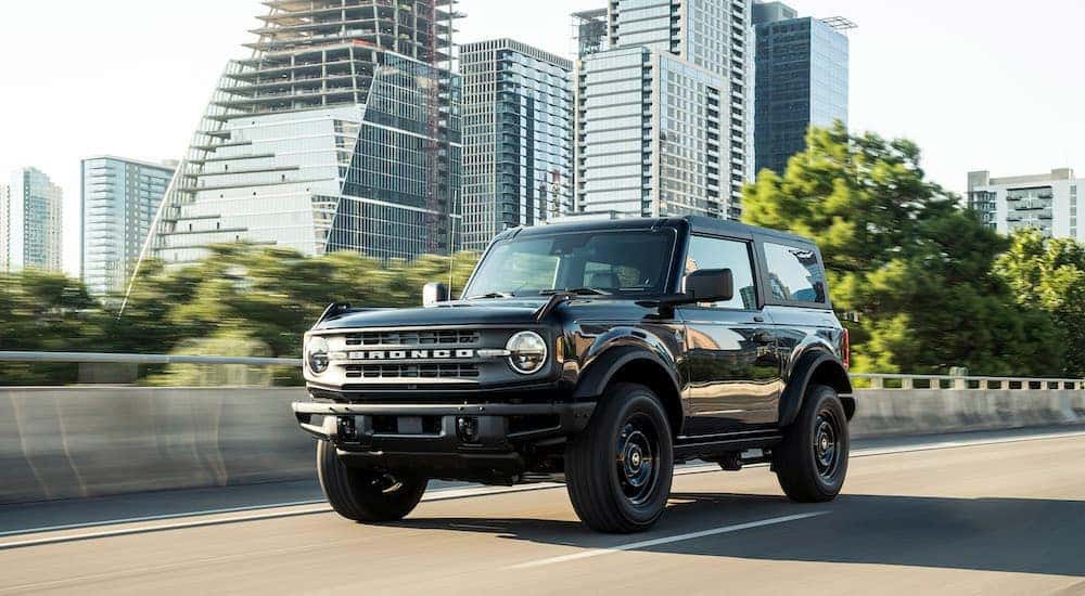 A black 2021 Ford Bronco Black Diamond is driving past buildings.