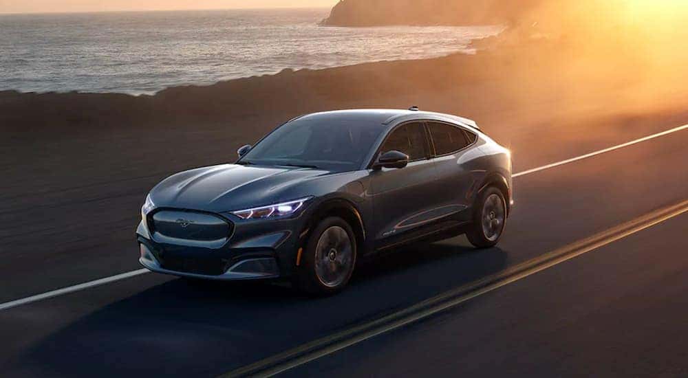 A grey 2021 Ford Mustang Mach-E is driving to a Ford dealer near Ionia.