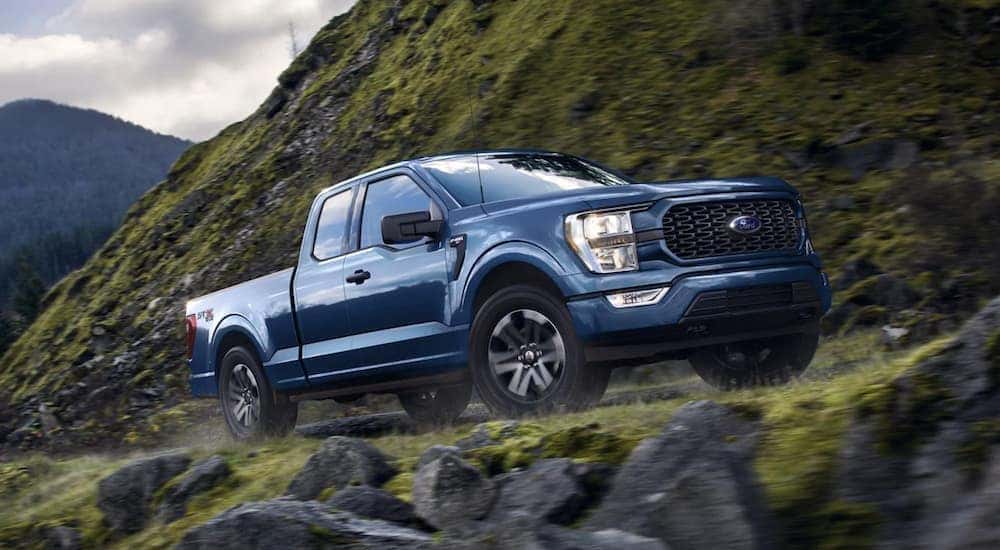 A blue 2022 Ford F-150 is off-roading in the mountains.