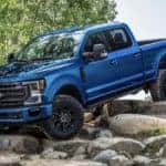 A blue 2022 Ford F-250 is shown parked on rocks.
