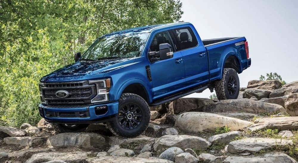 A blue 2022 Ford F-250 is parked on rocks.