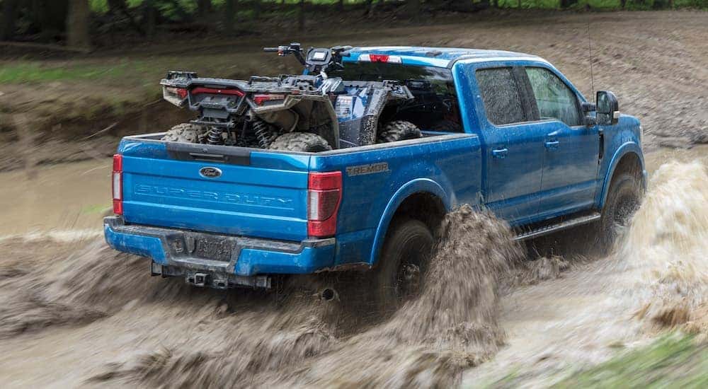 A blue 2021 Ford F-250 Tremor is driving to a used truck dealer near DeWitt.
