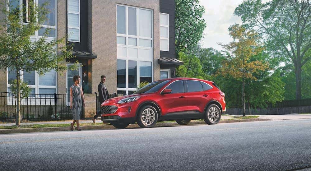 A red 2022 Ford Escape is driving on a city street.