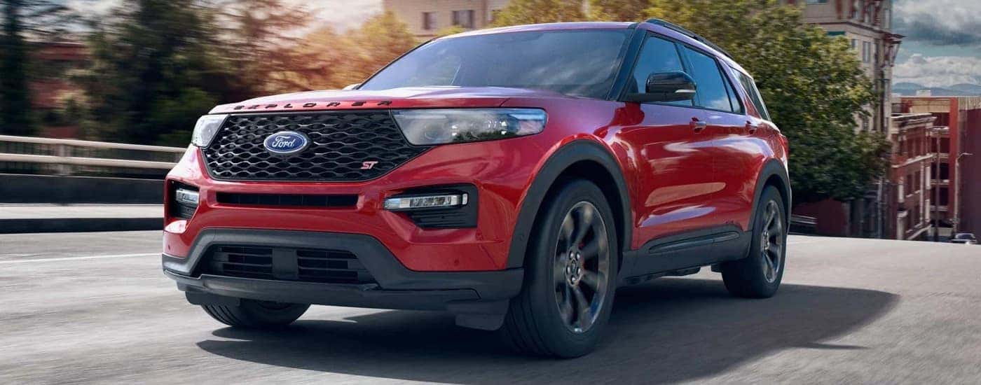 A red 2022 Ford Explorer ST is driving near a Ford dealer in Ionia.