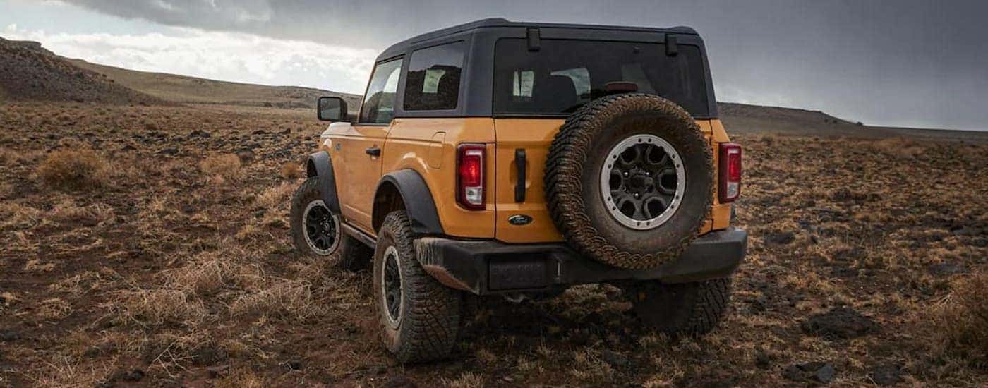 A yellow 2021 Ford Bronco is parked off-road.