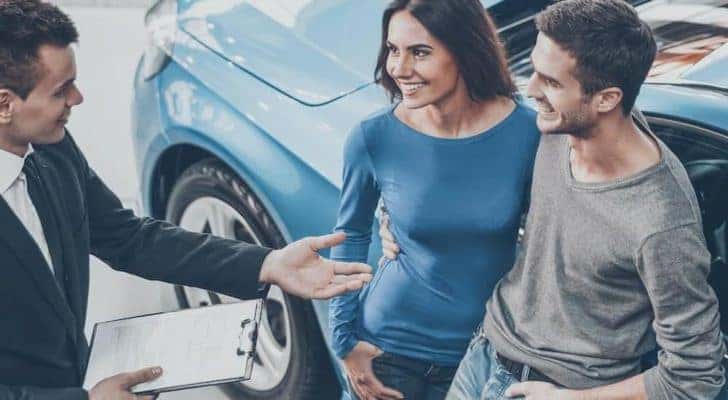 A salesperson is talking to a couple at a Ford dealer in Saint Johns.