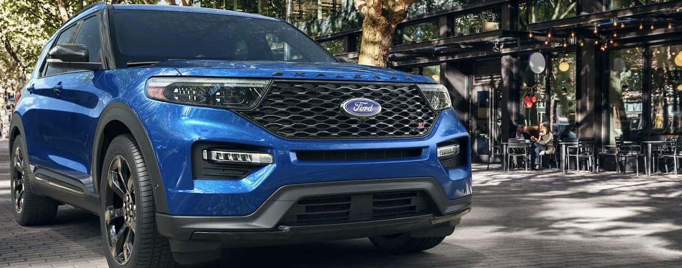 A blue 2022 Ford Explorer ST is parked outside of a small city cafe.