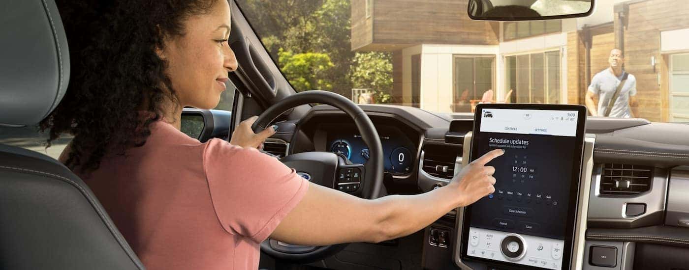 A person is using the infotainment system in a 2022 Ford F-150 Lightning at a Ford dealership near Grand Ledge.