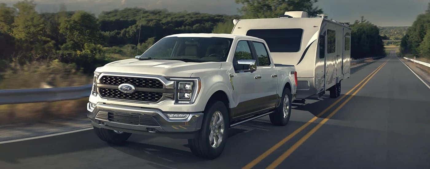 A white 2023 Ford F-150 is towing a camper trailer to a Ford dealership in Central Michigan.