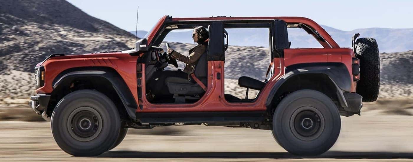 An orange 2022 Ford Bronco is driving off-road.