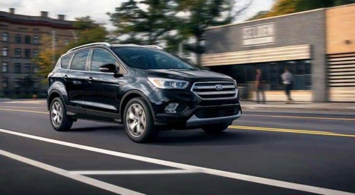 A black 2019 Ford Escape is shown driving through the center of a town.