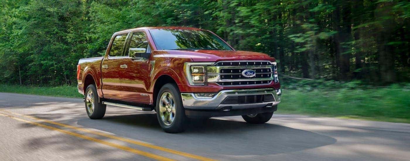 A red 2021 Ford F-150 is driving to a used truck dealer near Dewitt.