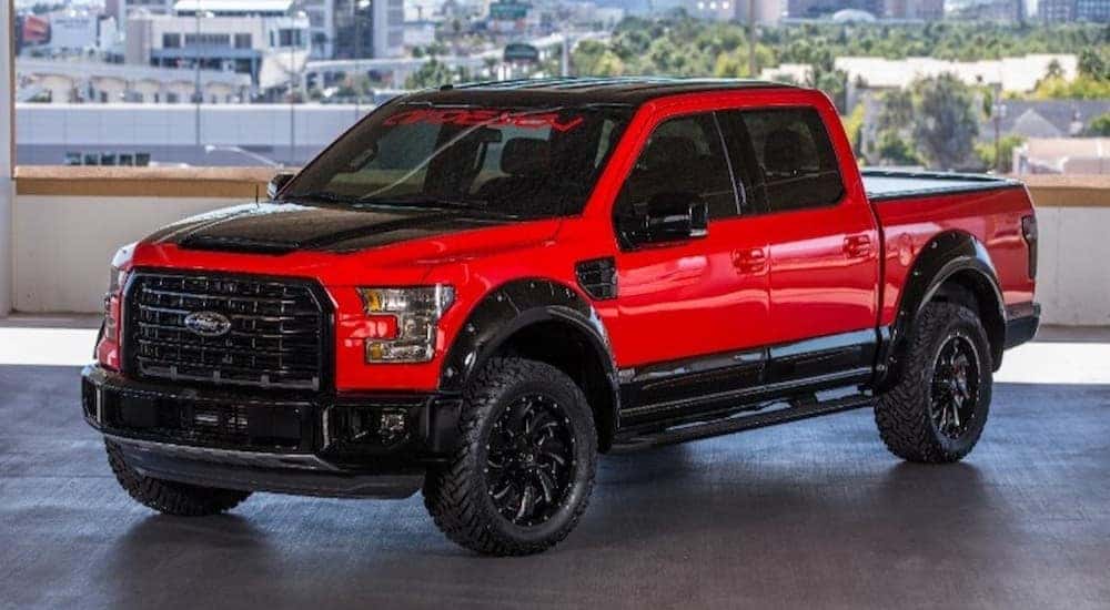 A red and black 2015 Ford F-150 is parked in a parking garage.