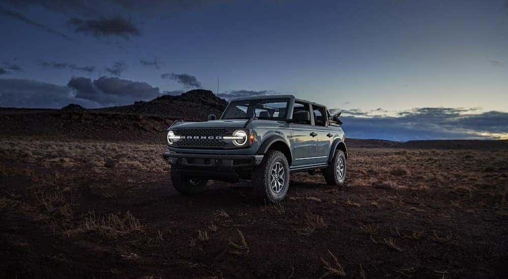 A blue 2024 Ford Bronco Badlands is parked near a Ford dealership.