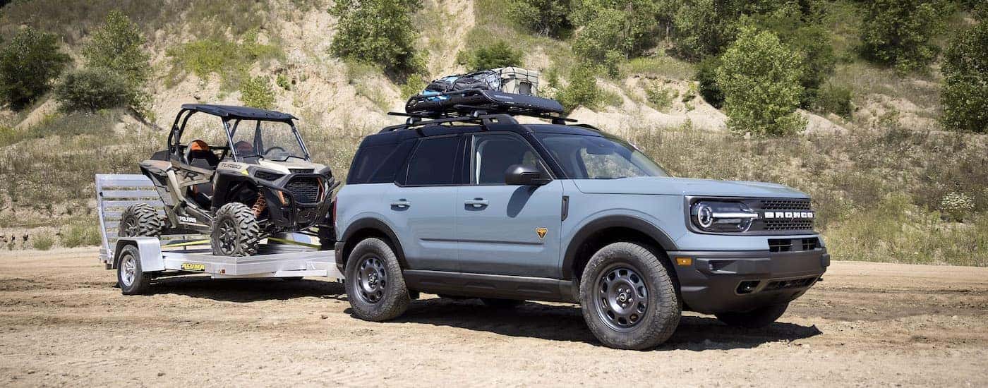 A blue 2022 Ford Bronco Sport is towing a UTV.