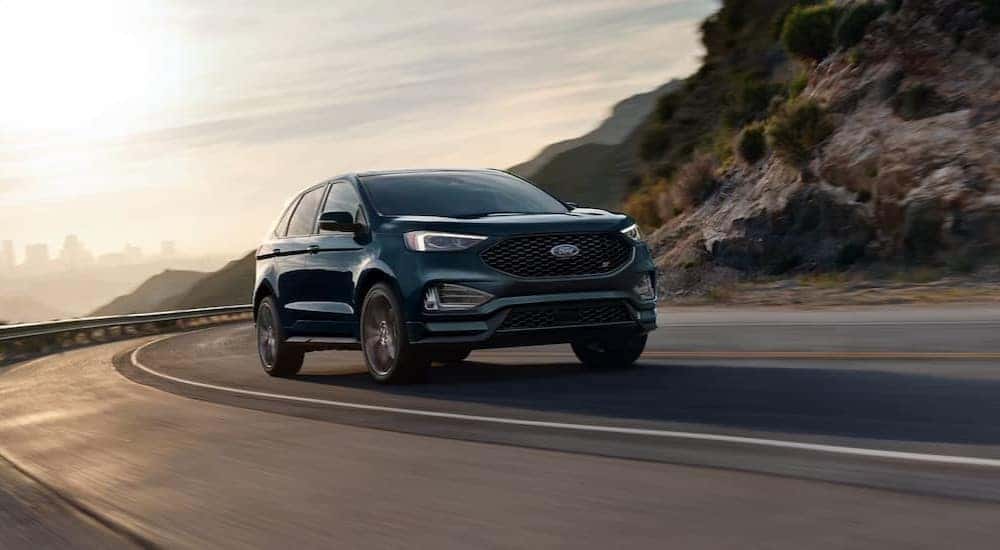 A blue 2024 Ford Edge is driving on a highway.