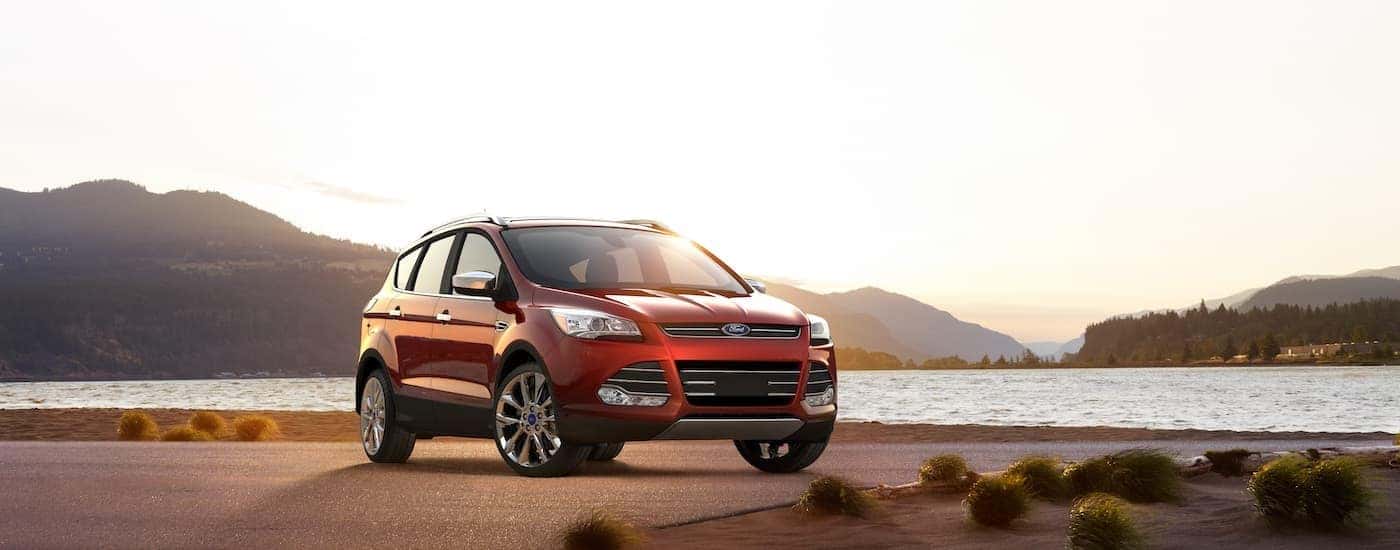 A red 2016 Ford Escape is parked near a lake after visiting a used car dealer near Lansing.
