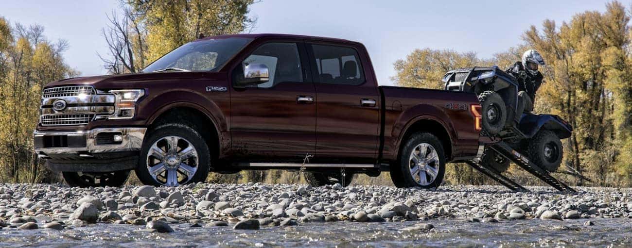 A burgundy 2020 Ford F-150 is shown parked near a stream.