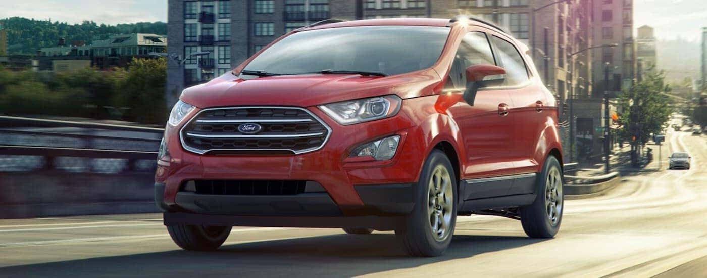 A red 2021 Ford EcoSport is shown driving on a city street.