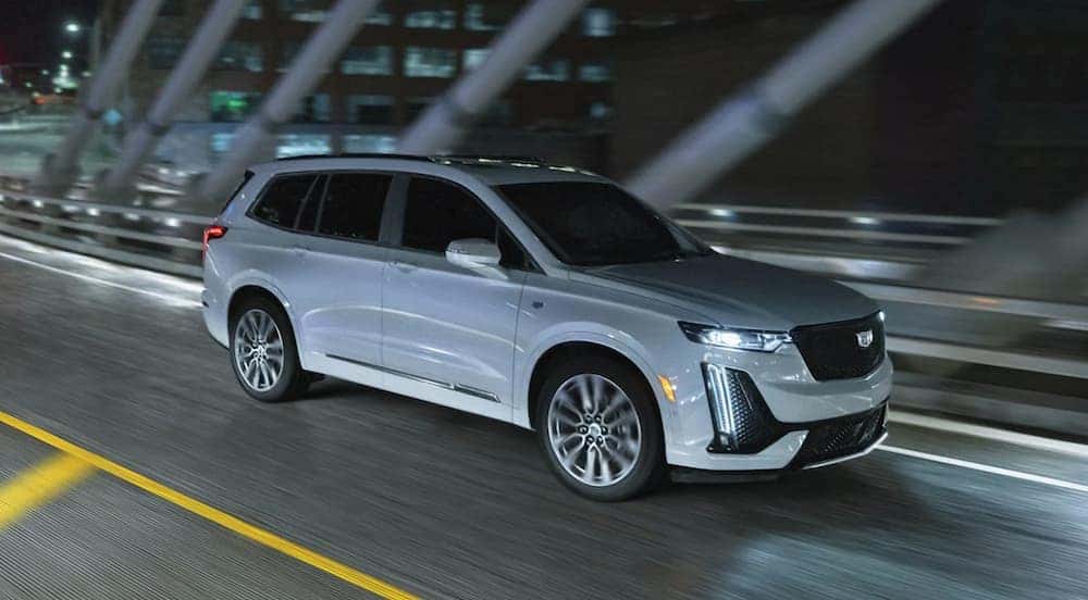 A white 2021 Cadillac XT6 is shown driving on a bridge.