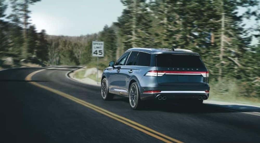 A blue 2023 Lincoln Aviator is driving on a highway.
