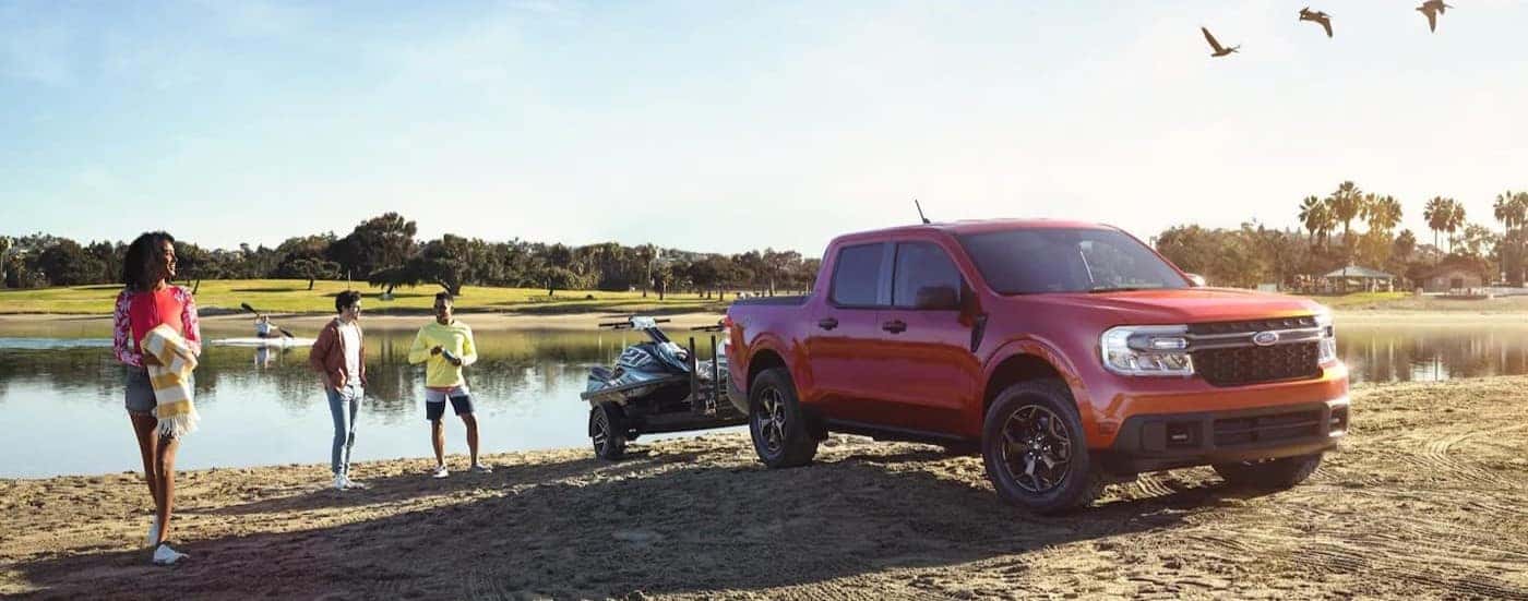 A red 2023 Ford Maverick FX4 is shown parked near a lake after visiting a used car dealer near Ionia.