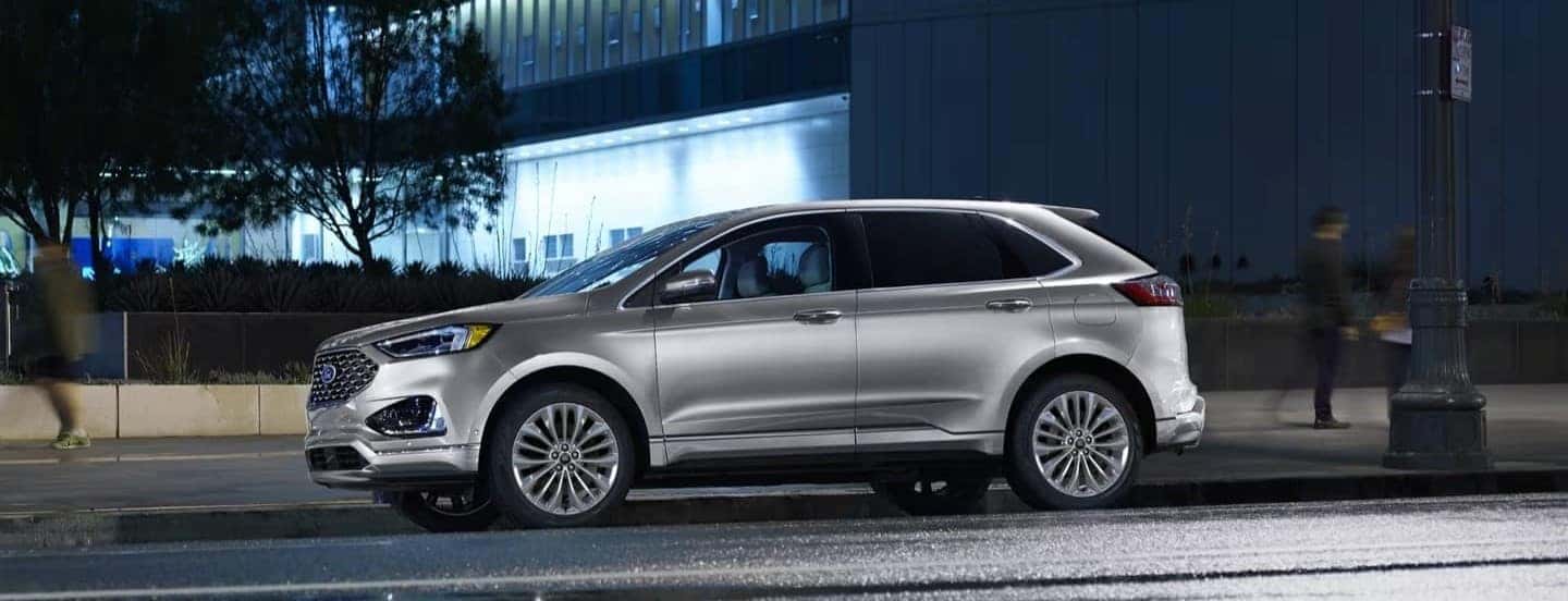 A silver 2023 Ford Edge is parked near a city curb.