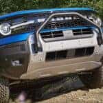 Close-up on the grille and headlights of a blue 2025 Ford Bronco Sport driving up a hill.
