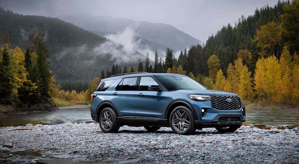 A blue 2025 Ford Explorer ST is parked near a lake.