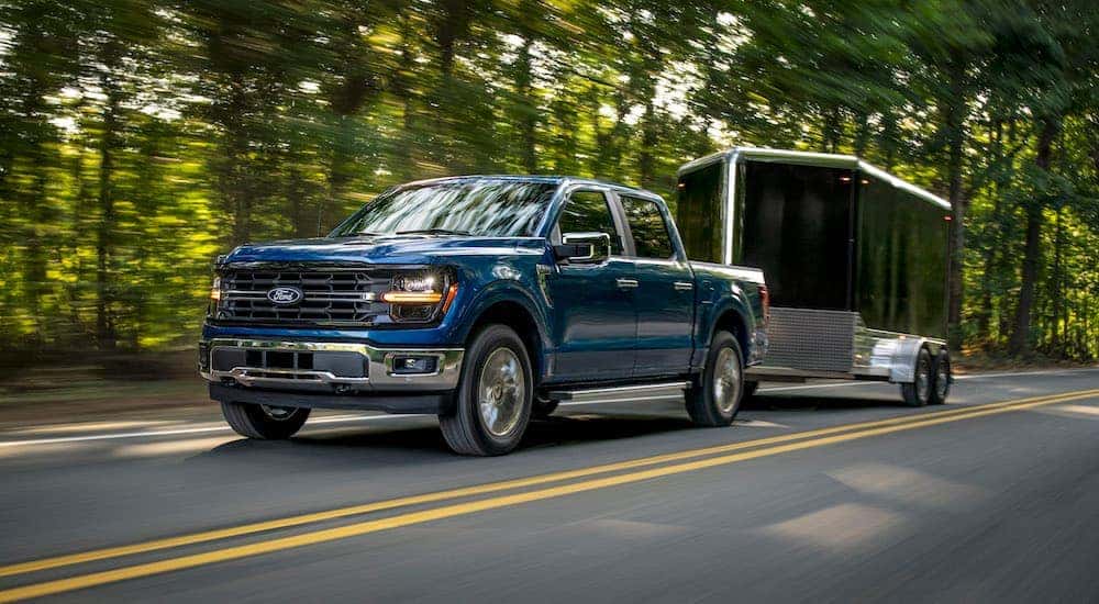 A blue 2025 Ford F-150 XLT towing a trailer.