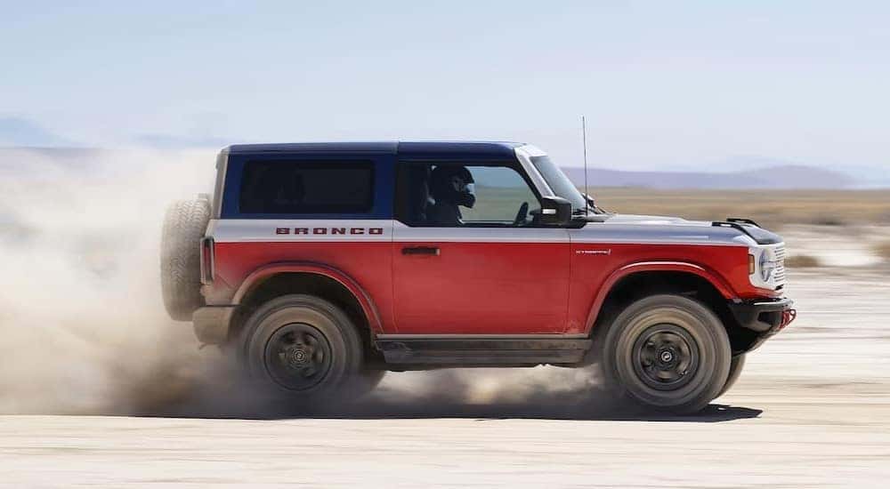 A mostly red 2025 Ford Bronco Stroppe Edition driving off-road.