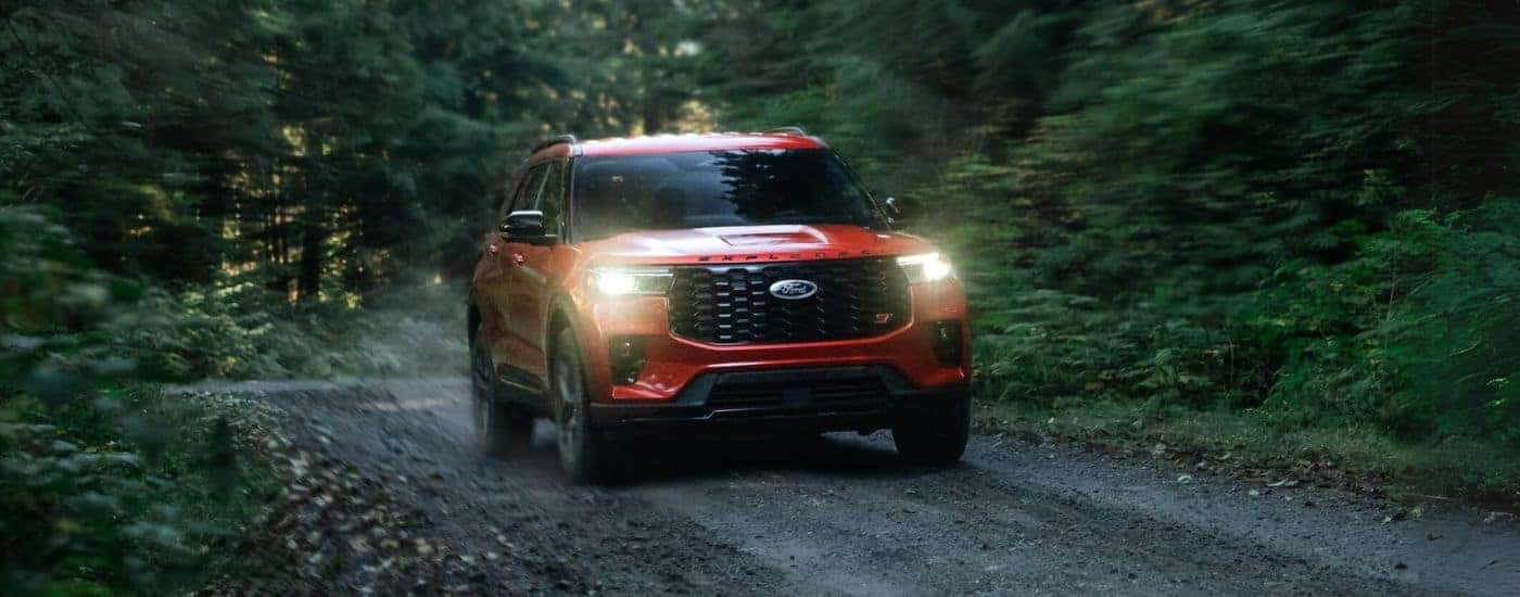 Red 2025 Ford Explorer ST for sale near Lansing driving through a forest.