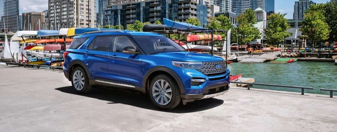 Blue 2024 Ford Explorer Limited driving by a lake.