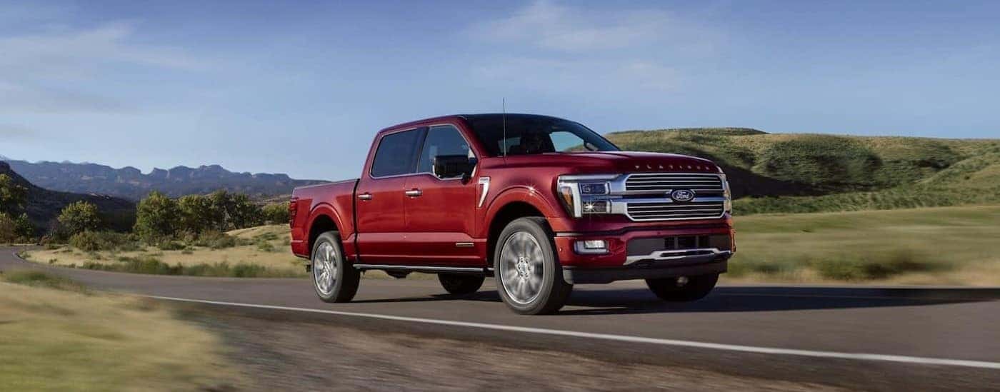 A red 2025 Ford F-150 for sale near me driving on a highway.