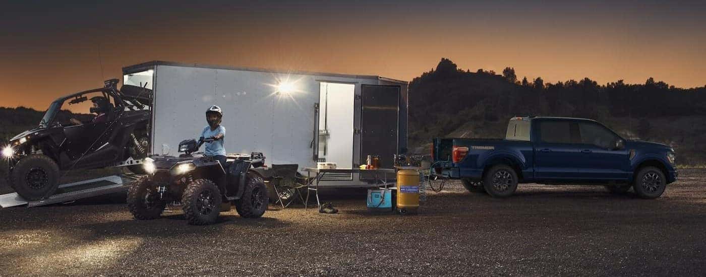 A blue 2025 Ford F-150 towing a trailer.