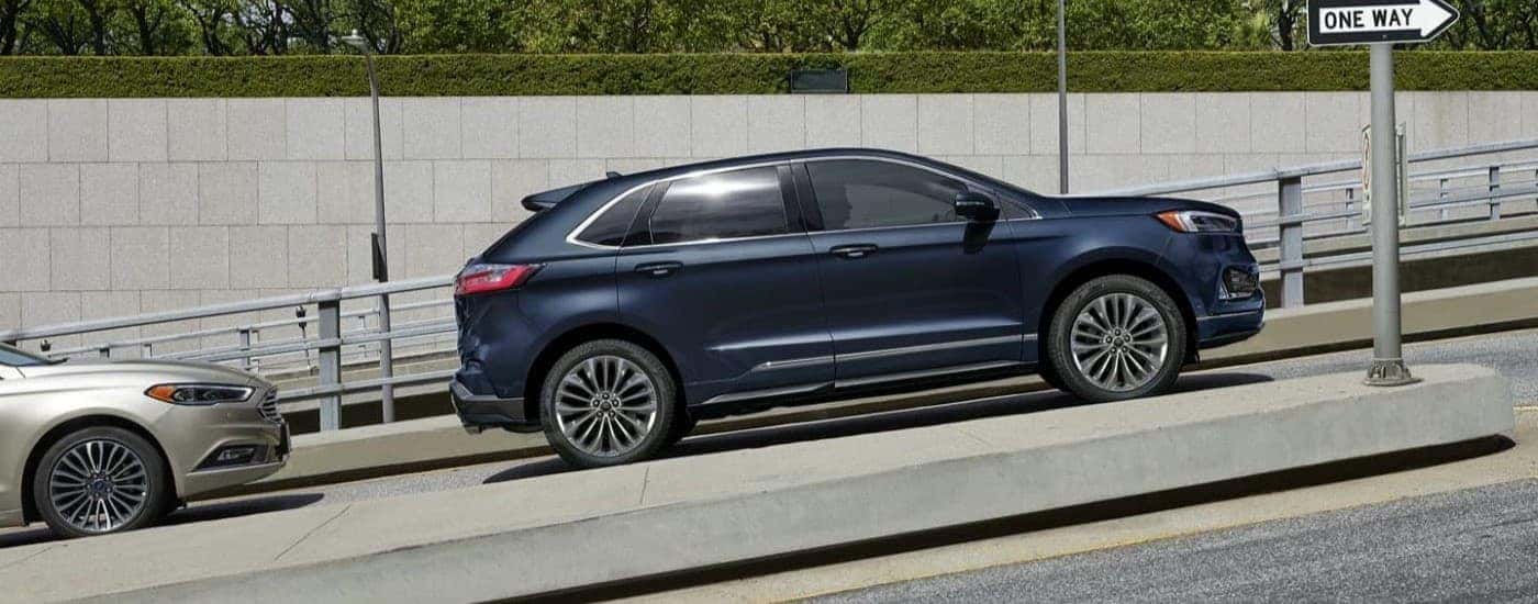 A dark blue 2023 Ford Edge is driving to a Ford dealer in Ionia.