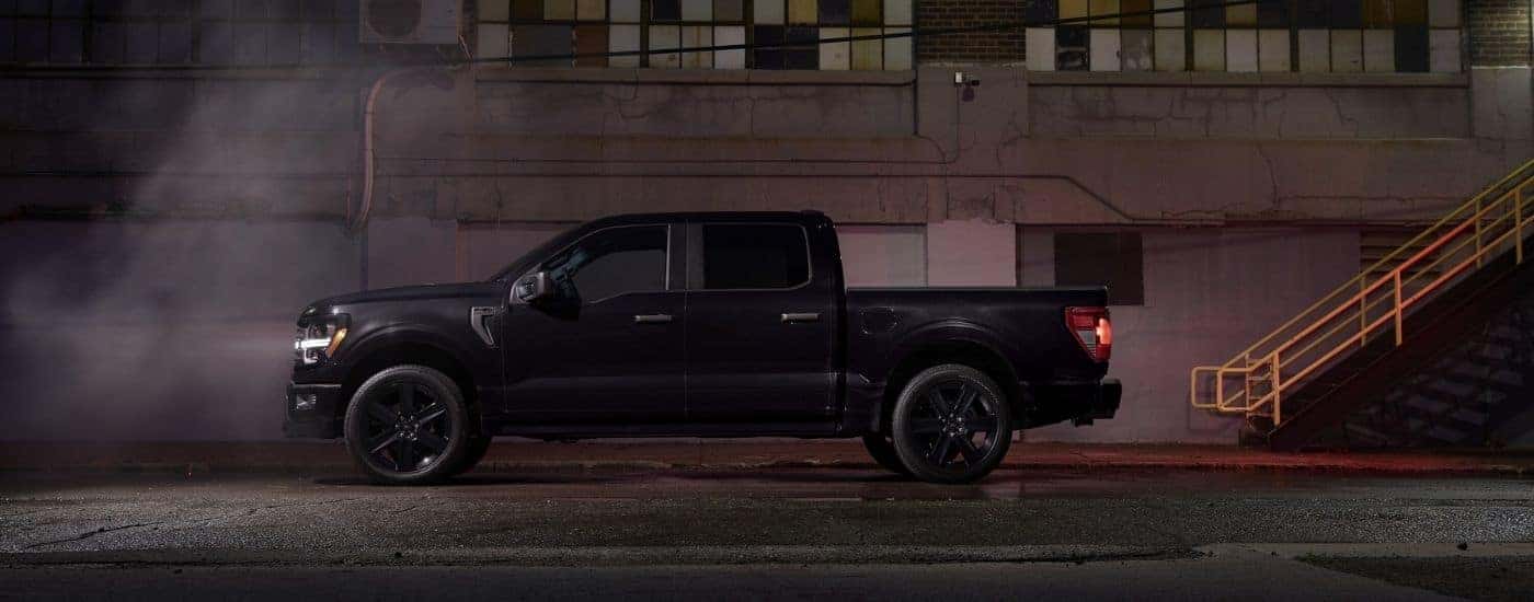 A black 2025 Ford F-150 Lobo in front of a warehouse.