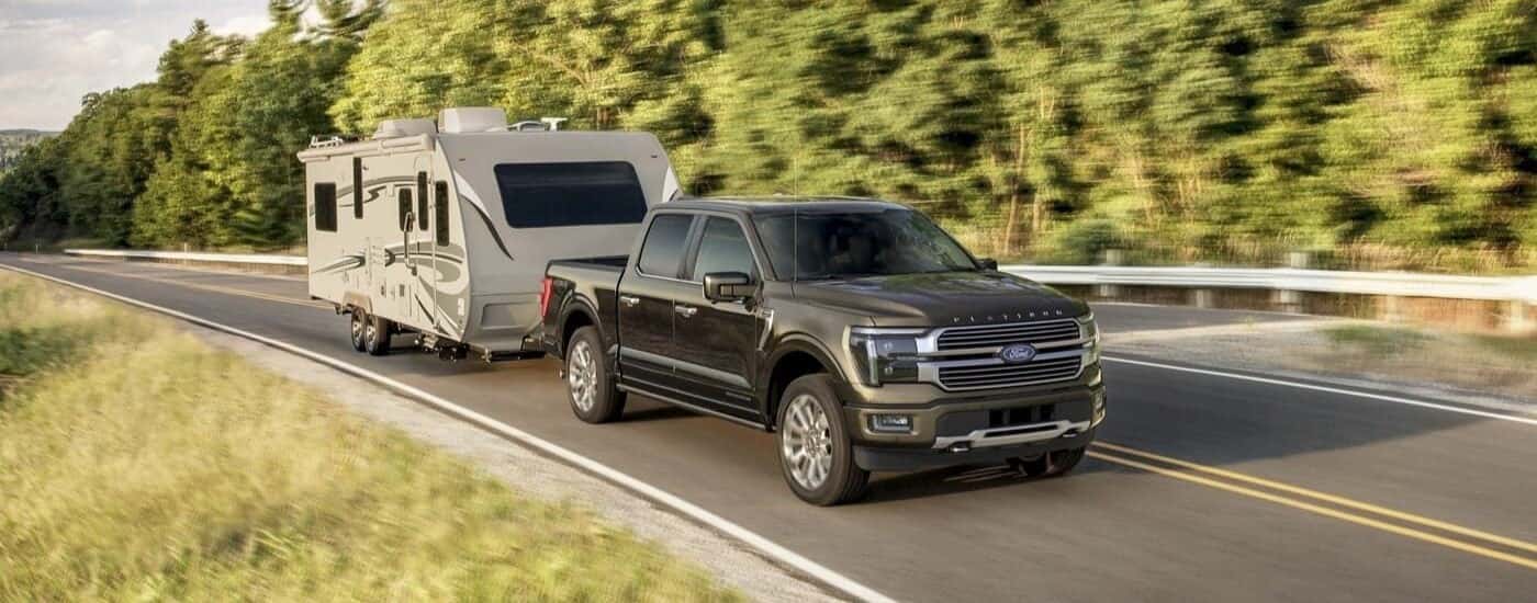A gray 2024 Ford F-150 Platinum is towing a trailer.