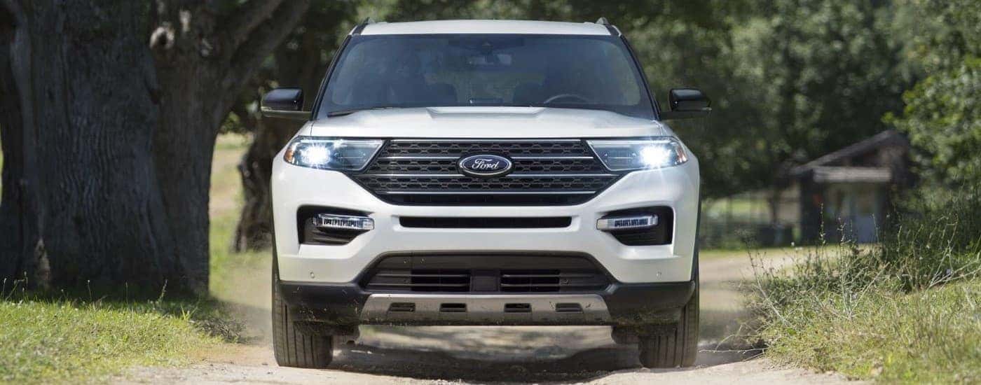 A white 2023 Ford Explorer King Ranch is driving on a dirt road.