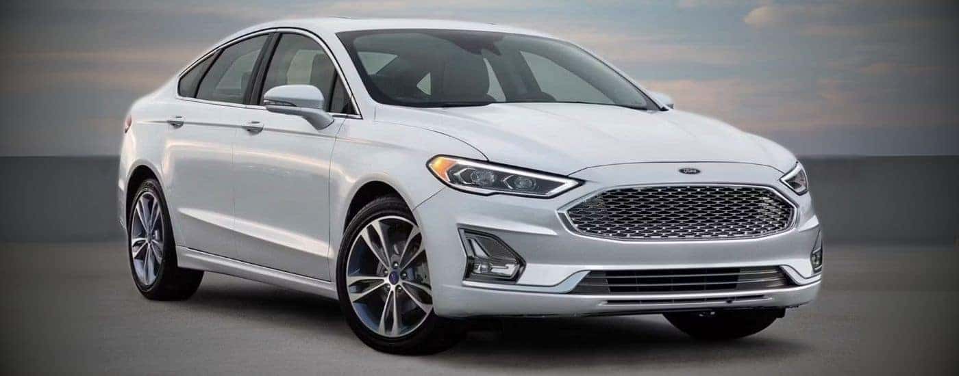 A white 2020 Ford Fusion parked at a used car dealer near Owosso.