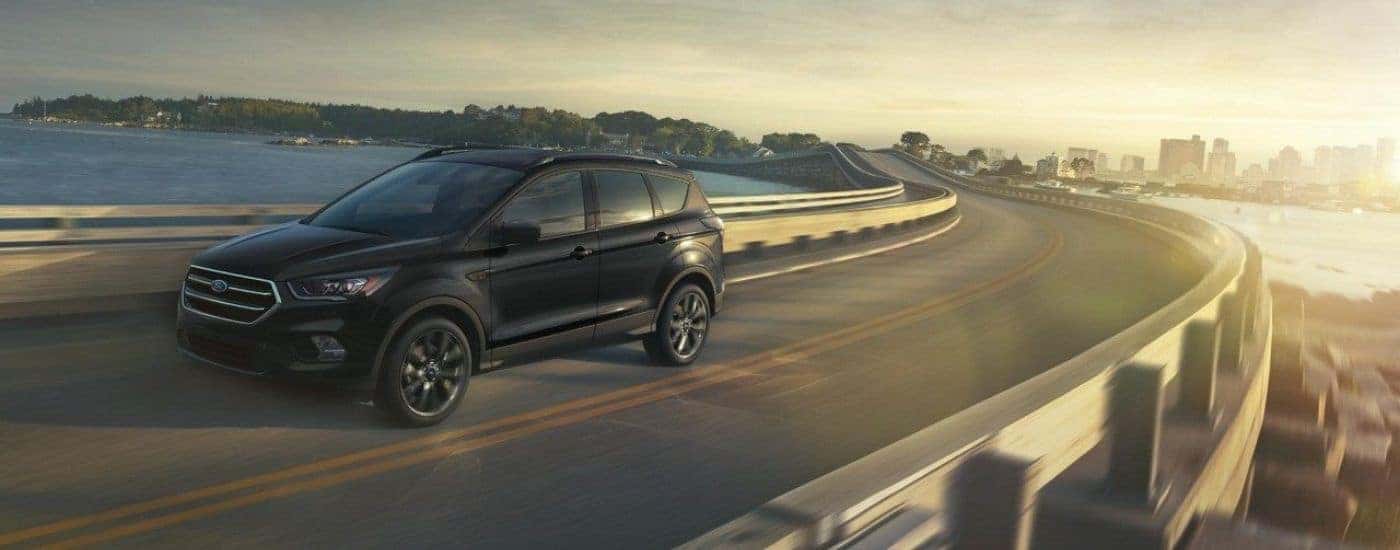 An black 2018 Ford Escape is driving to a used car dealership.