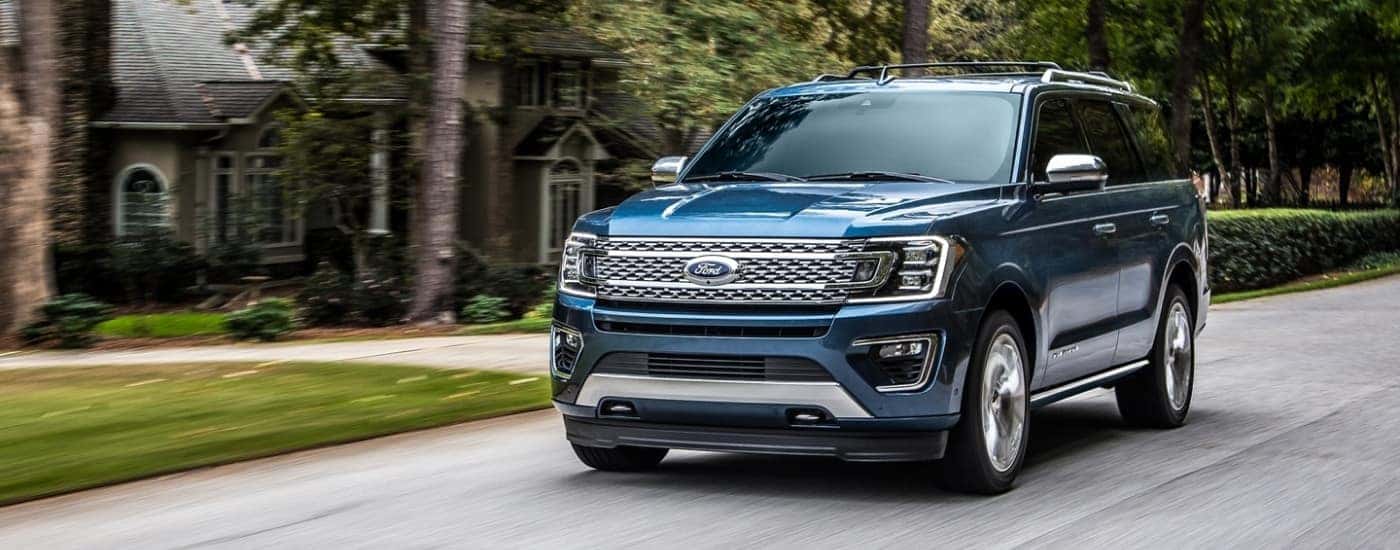 A blue 2020 Ford Expedition is driving to a used Ford dealership.