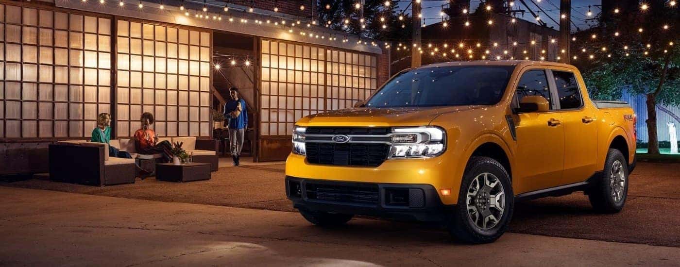 A yellow 2023 Ford Maverick under lights at night.