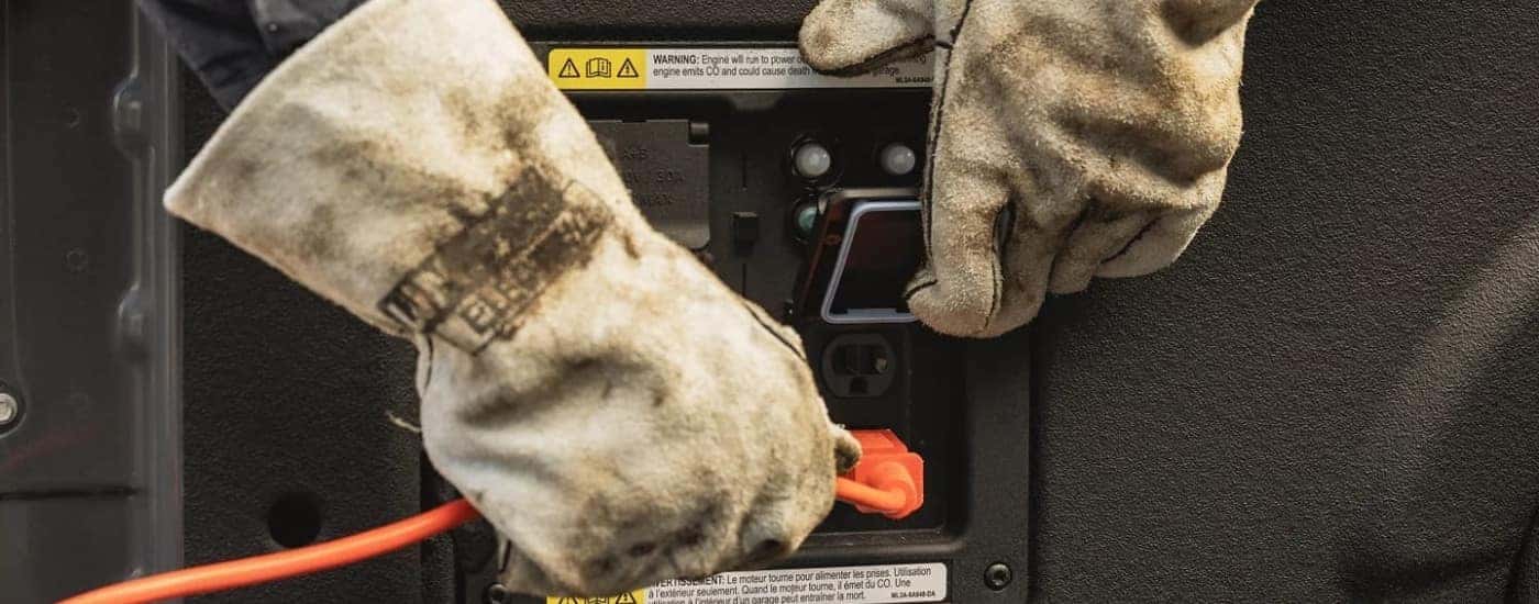 Gloved hands plugging a chord into the bed of a 2023 Ford F-150.