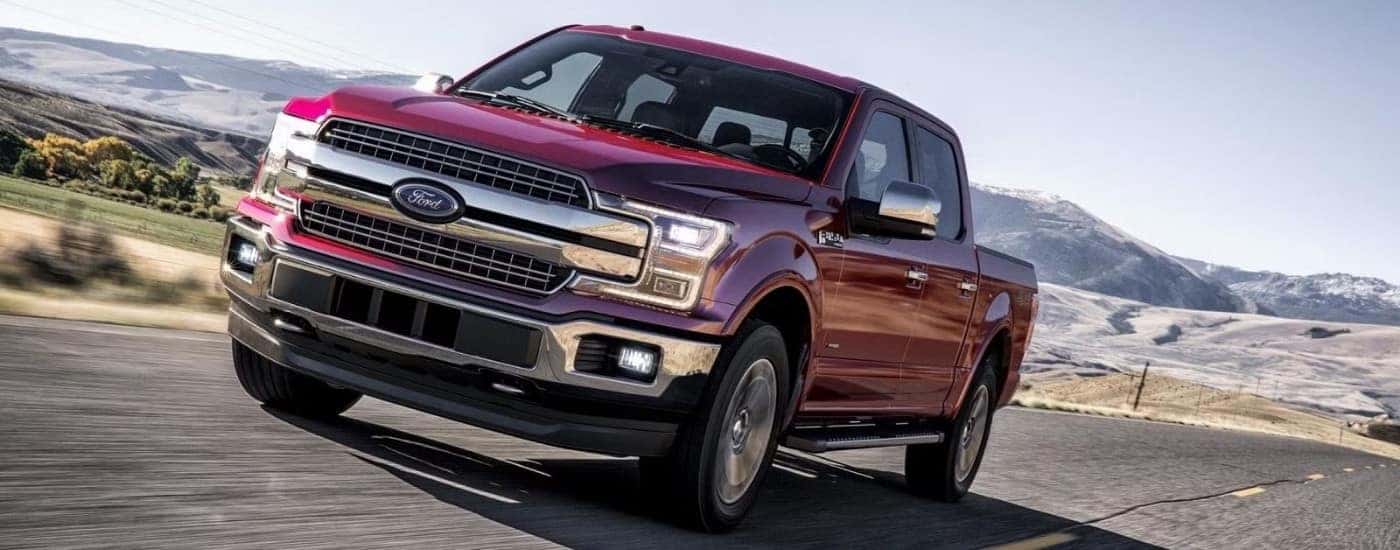 A red 2019 Ford F-150 Lariat is shown driving on a highway after visiting a used truck dealer near Lansing.