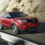 A used red 2019 Ford Explorer for sale is driving on a highway.